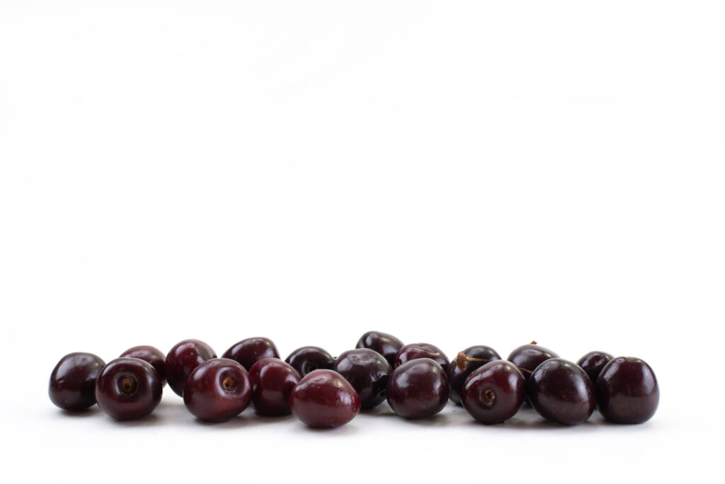 A pile of fresh açai berries on a white background, showcasing their deep purple color.