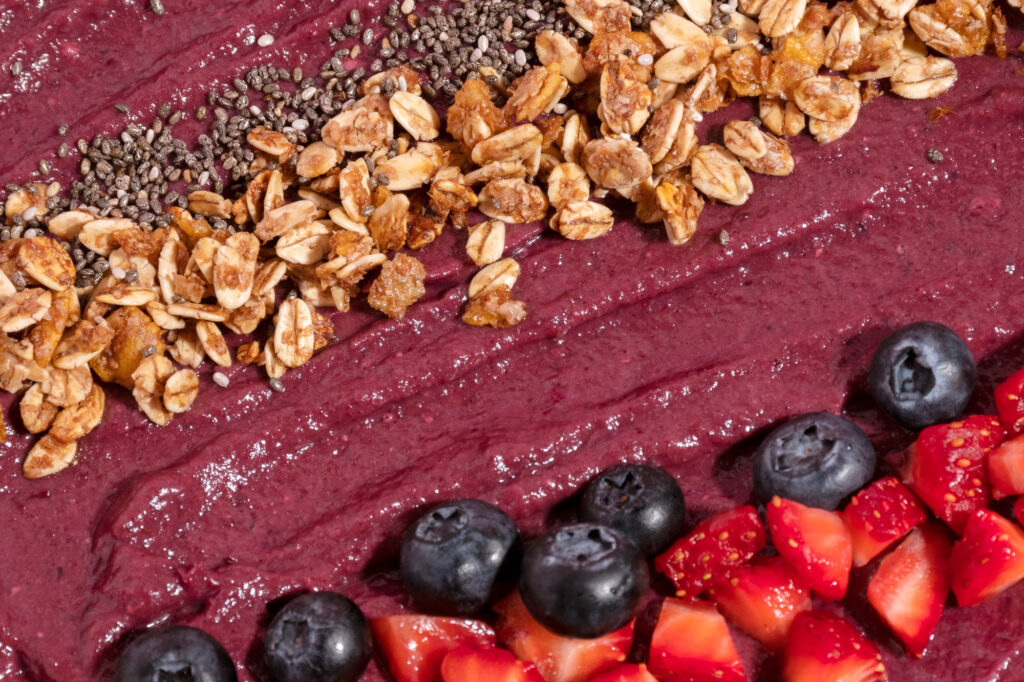 A close-up of a Healthy Food smoothie bowl topped with granola, chia seeds, and fresh berries.