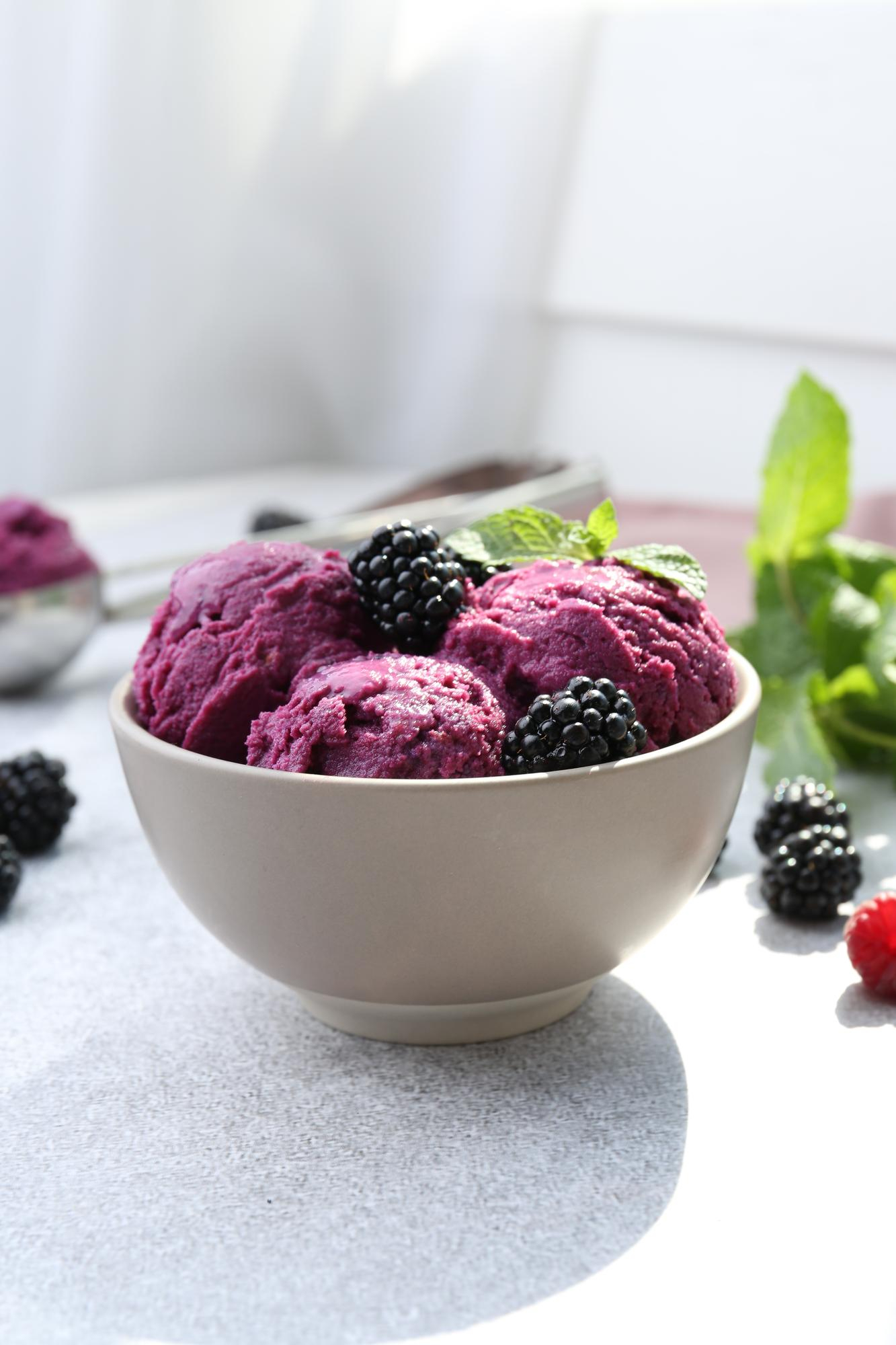 Vegan açaí sorbet scoops in a ceramic bowl with fresh blackberries and mint – healthy frozen dessert