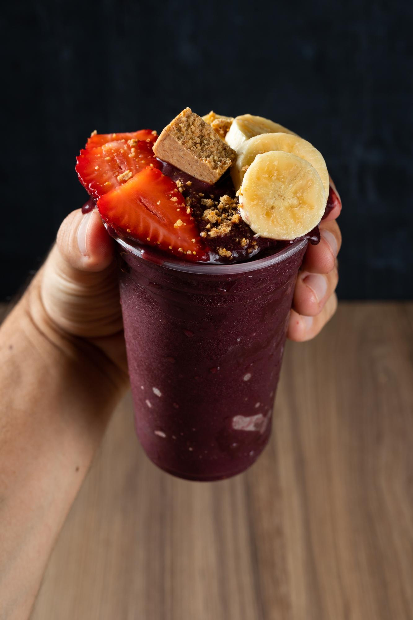 Takeaway açaí bowl topped with banana, strawberry, and peanut butter – nutritious and energizing snack