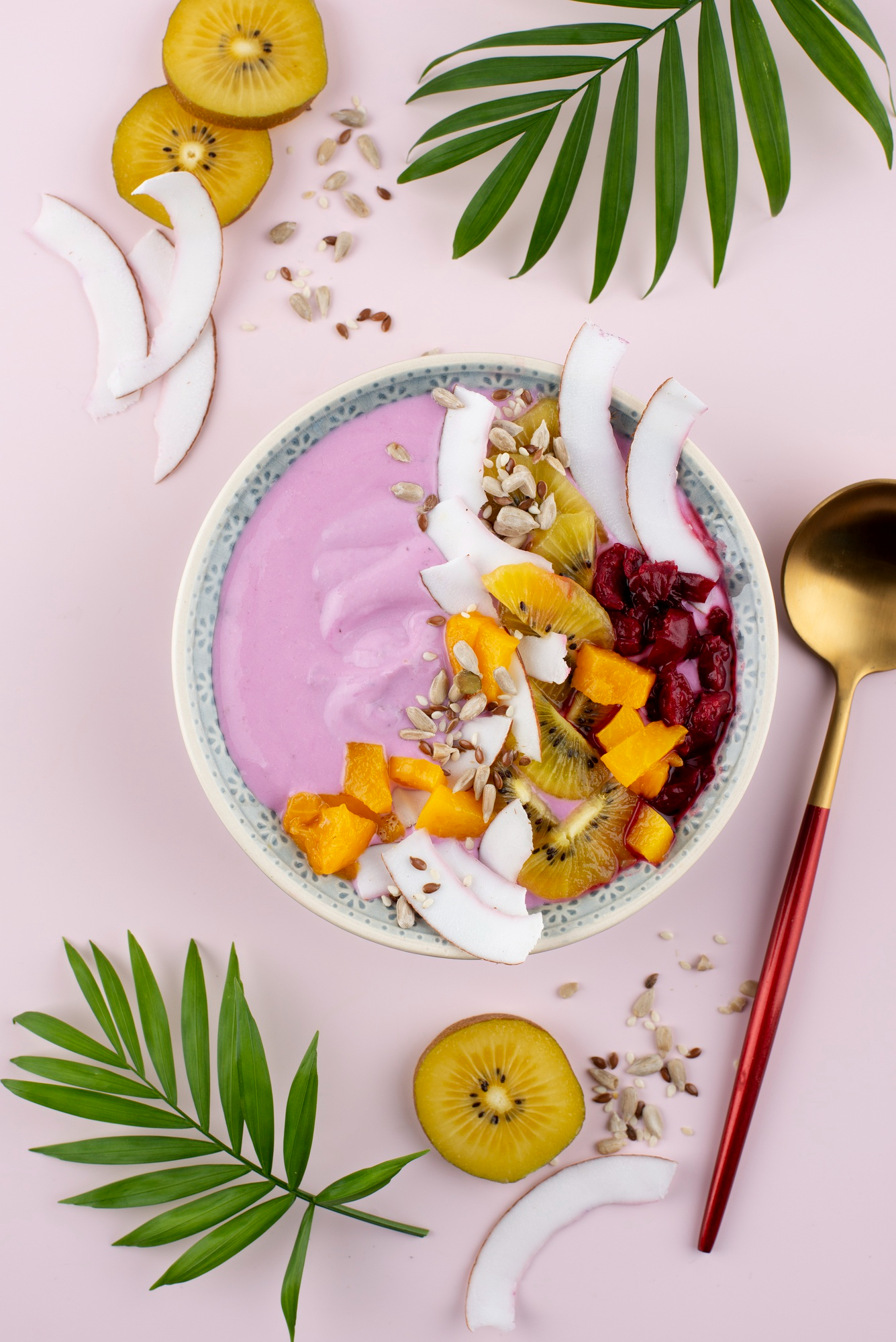 Bright pink açaí smoothie bowl with golden kiwi, coconut chips, flax seeds, and tropical fruits – vegan and gluten-free superfood