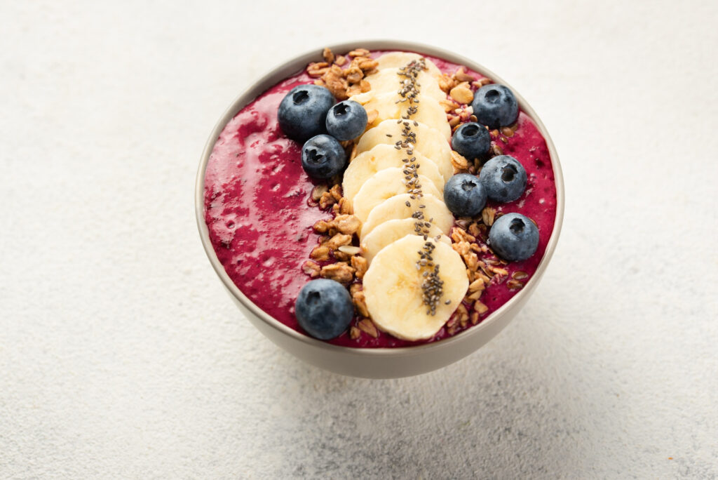 Açaí smoothie bowl with banana slices and chia seeds prepared following certification bio food manufacturing standards