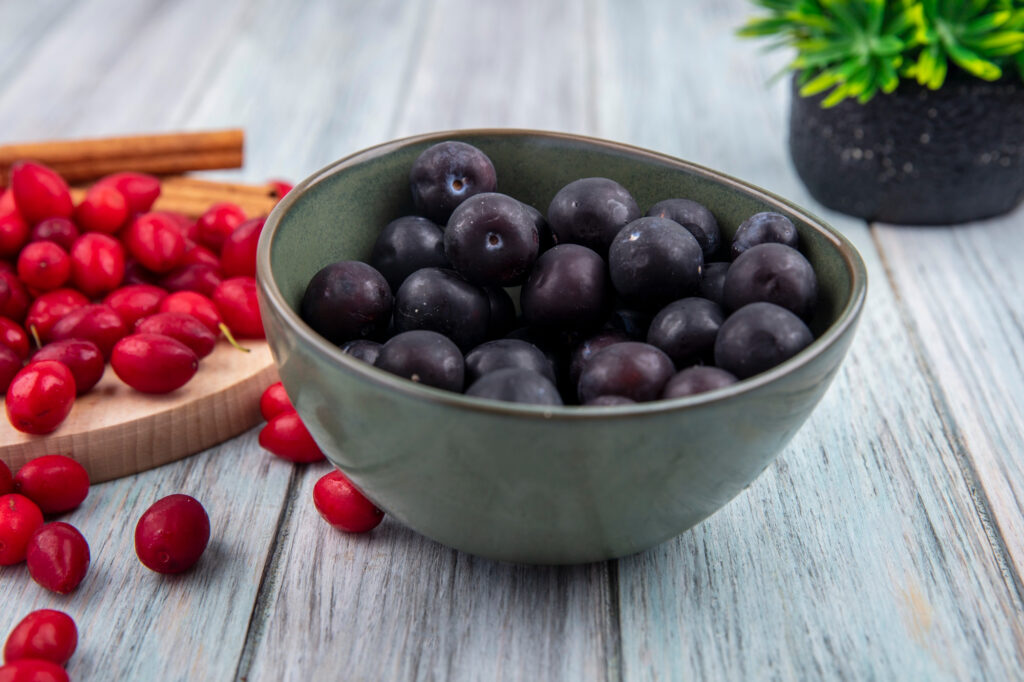 Bowl of fresh dark berries and cranberries on wooden table demonstrating natural sources of açaí antioxidants