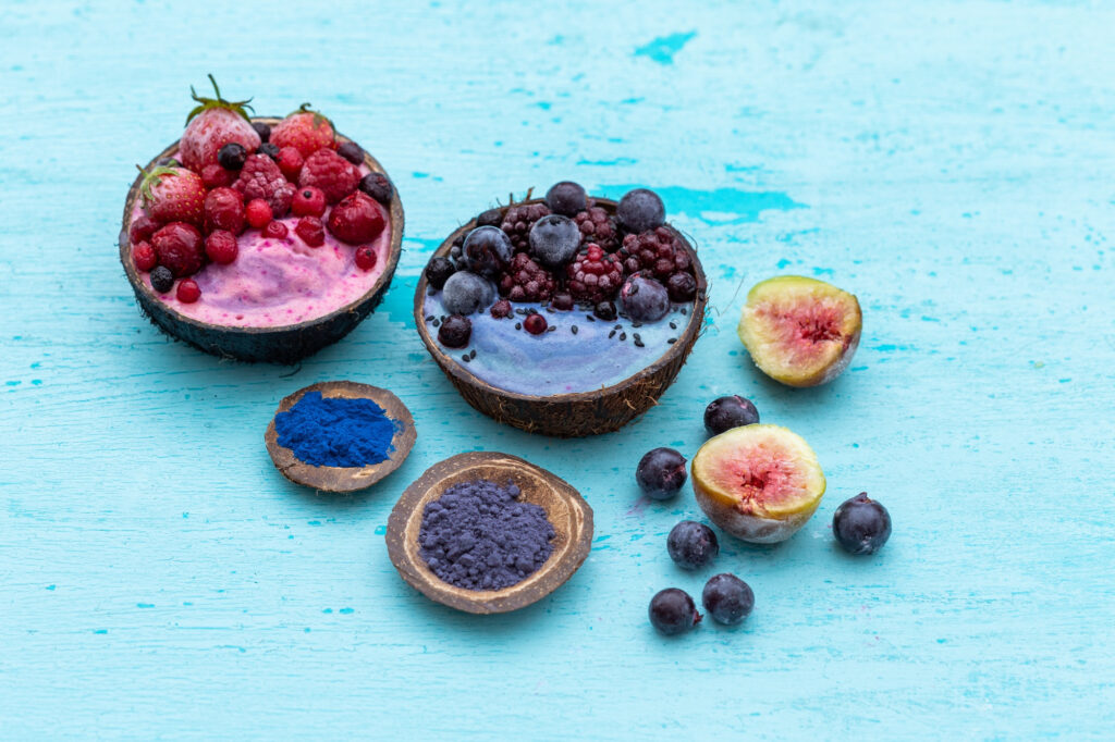 Colorful açaí bowls and superfood powders on blue surface highlighting different forms of açaí antioxidants