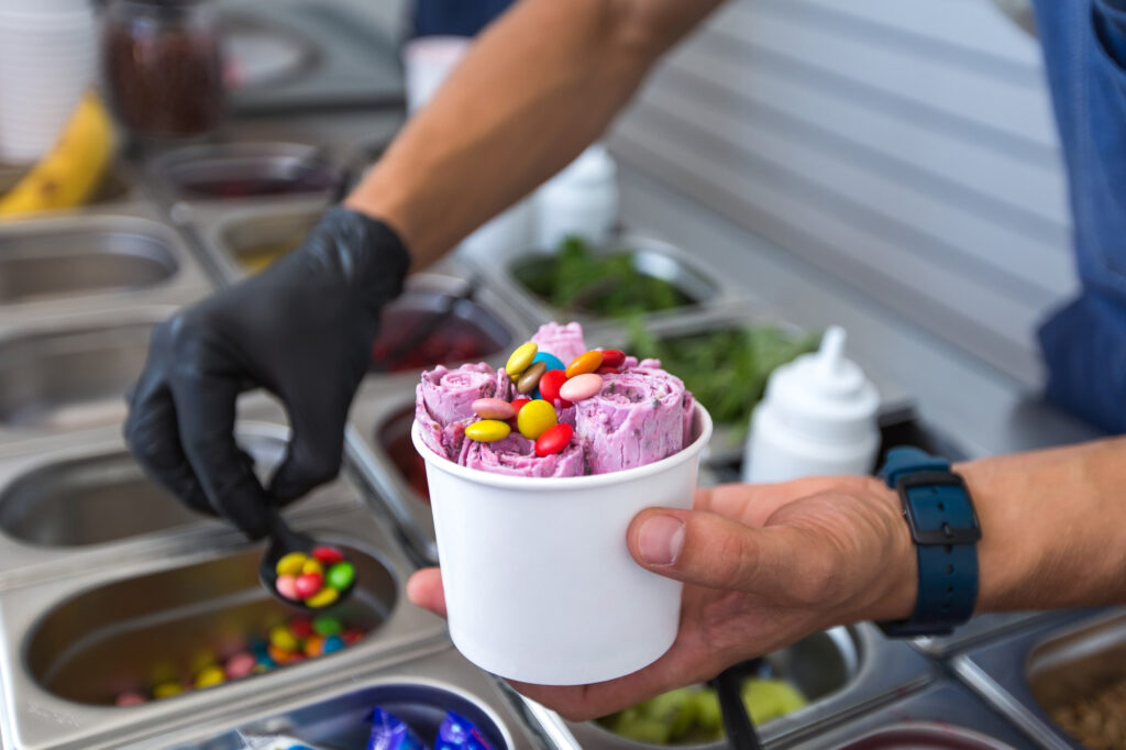 Professional açaí ice cream preparation with colorful toppings for healthy food delivery service