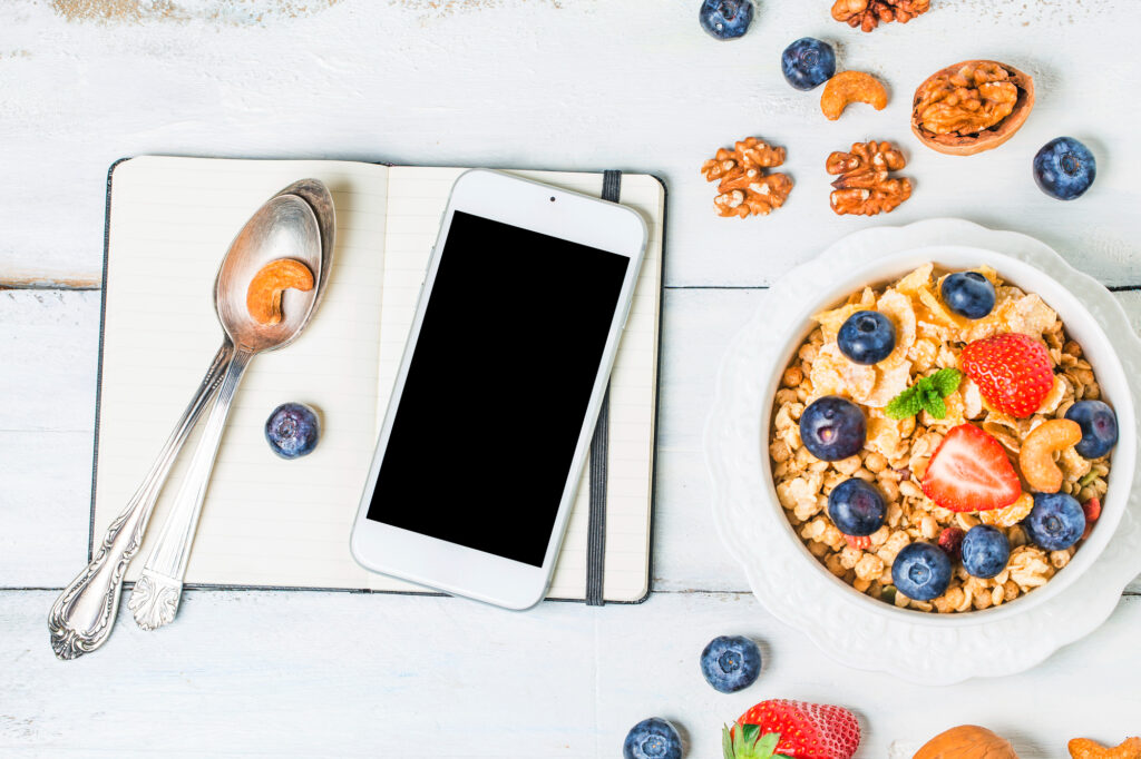Granola with fresh fruits and nuts with smartphone for online healthy food delivery ordering