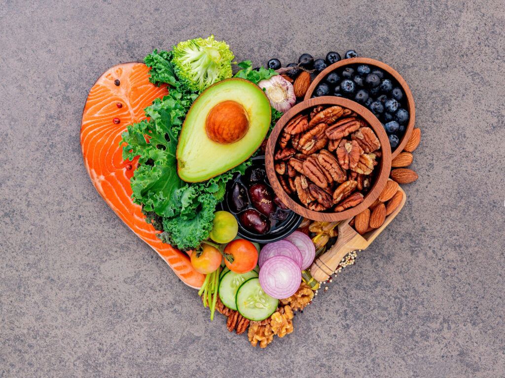 Microbiome diet heart-shaped arrangement of salmon, avocado, nuts, berries and leafy greens promoting cardiovascular and gut health